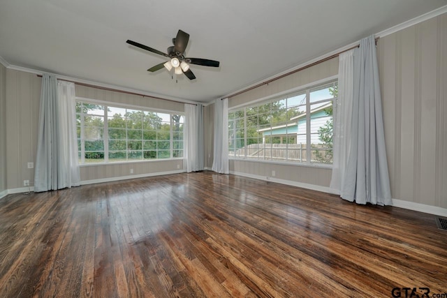 spare room with dark hardwood / wood-style floors, a healthy amount of sunlight, ornamental molding, and ceiling fan