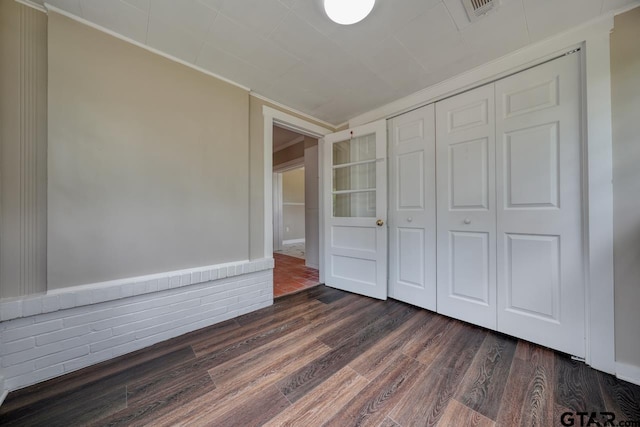 unfurnished bedroom with a closet and dark wood-type flooring