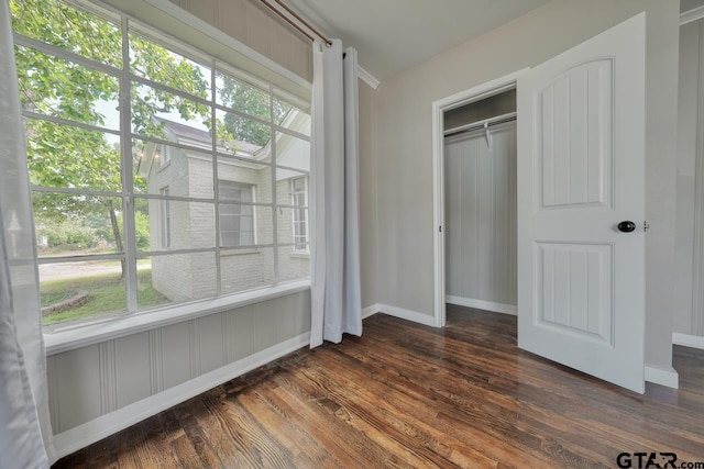 unfurnished bedroom with a closet, dark wood-type flooring, and multiple windows