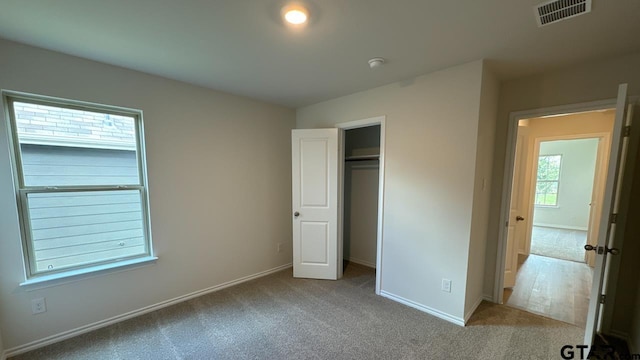 unfurnished bedroom featuring light colored carpet and a closet