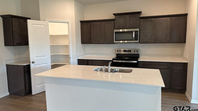 kitchen with an island with sink, stainless steel appliances, sink, and hardwood / wood-style floors