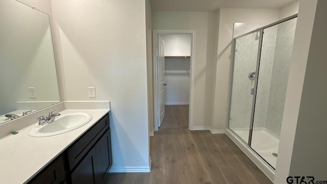 bathroom with walk in shower, vanity, and hardwood / wood-style flooring