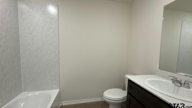 bathroom with vanity, a tub to relax in, and toilet