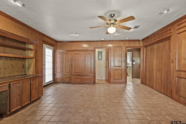 interior space featuring ceiling fan, ornamental molding, and wood walls