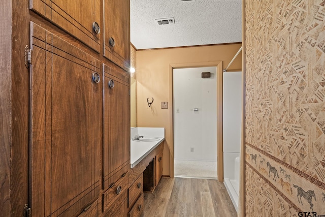 bathroom with vanity, wood-type flooring, a textured ceiling, and walk in shower