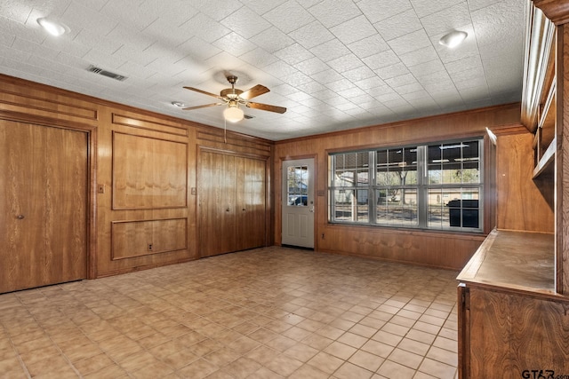 interior space with ceiling fan and wooden walls