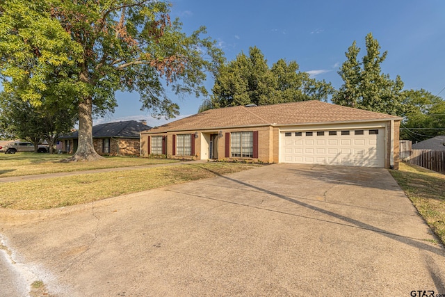 ranch-style home featuring driveway, an attached garage, fence, and a front yard