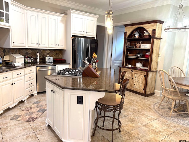 kitchen with stainless steel appliances, a center island, tasteful backsplash, white cabinetry, and decorative light fixtures