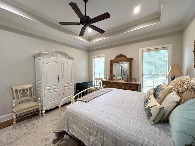 bedroom featuring ornamental molding, light hardwood / wood-style floors, ceiling fan, and a raised ceiling