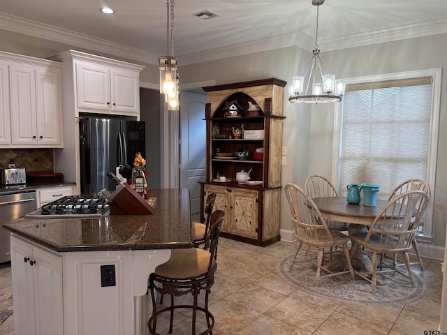 kitchen with stainless steel appliances, hanging light fixtures, white cabinetry, and a center island