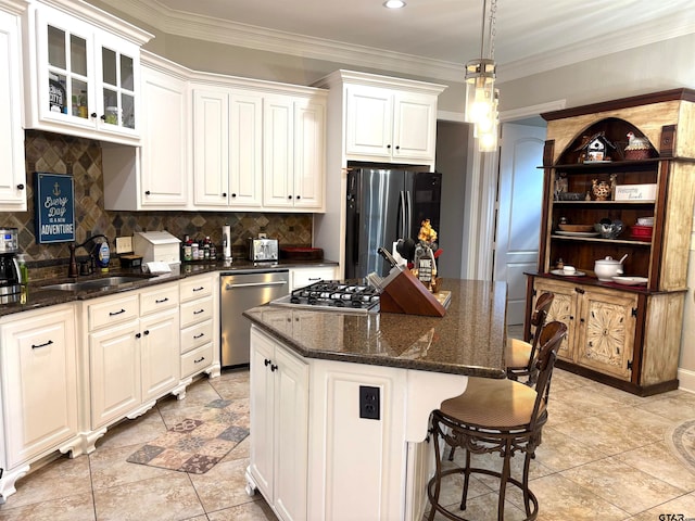 kitchen with stainless steel appliances, a center island, white cabinets, sink, and pendant lighting