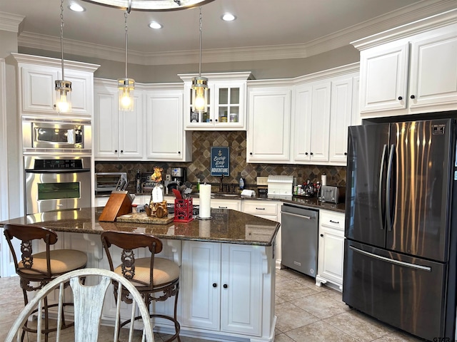 kitchen with dark stone counters, a center island, hanging light fixtures, white cabinetry, and appliances with stainless steel finishes