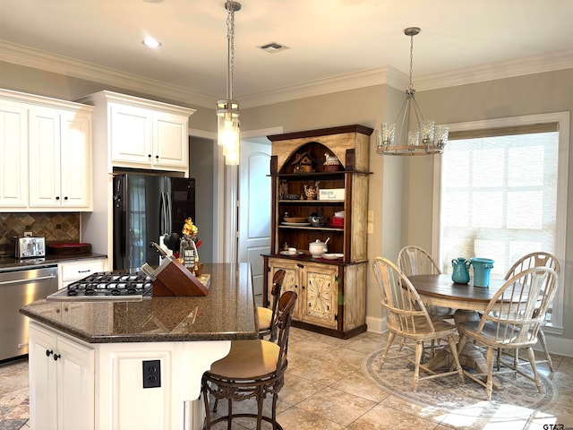 kitchen with white cabinets, stainless steel dishwasher, black fridge, and a center island