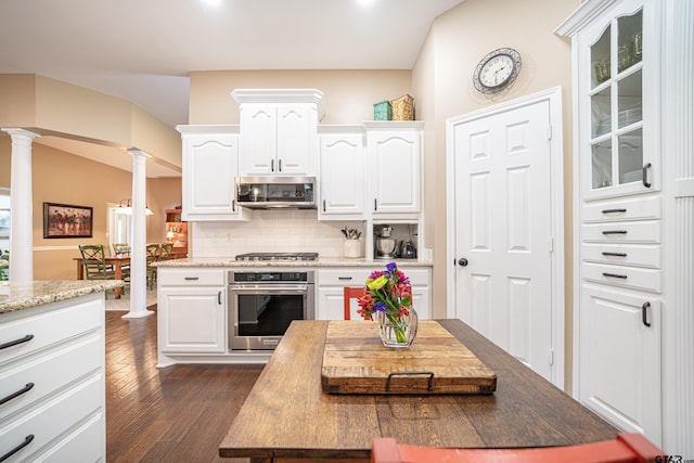 kitchen with stainless steel appliances, white cabinets, decorative backsplash, and ornate columns