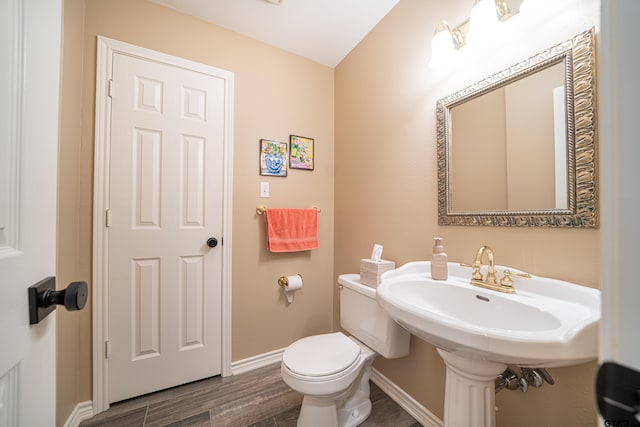 bathroom with toilet, baseboards, and wood finished floors