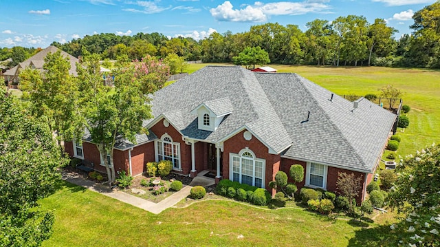 view of front facade featuring a shingled roof, brick siding, and a front lawn