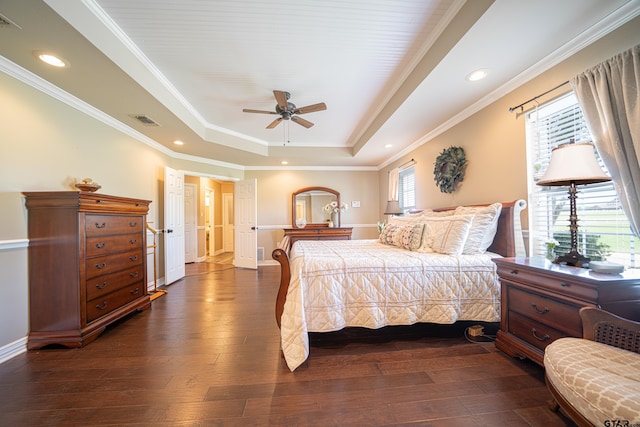 bedroom with a tray ceiling, dark wood finished floors, recessed lighting, visible vents, and ornamental molding