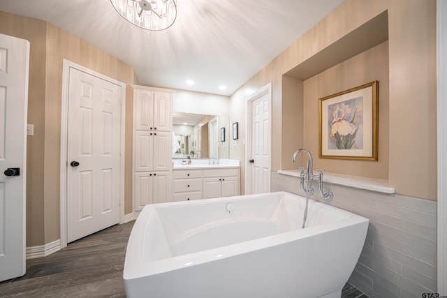 bathroom featuring wood finished floors, a freestanding tub, vanity, and recessed lighting