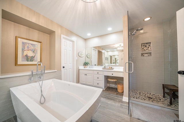 bathroom with recessed lighting, wood finished floors, vanity, a soaking tub, and a shower stall