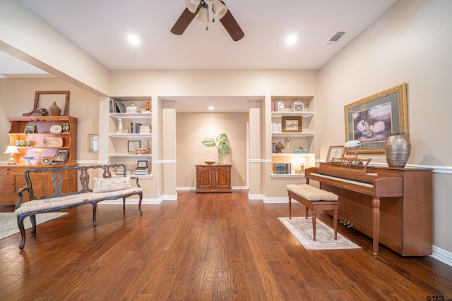 sitting room with built in features, visible vents, baseboards, and wood finished floors