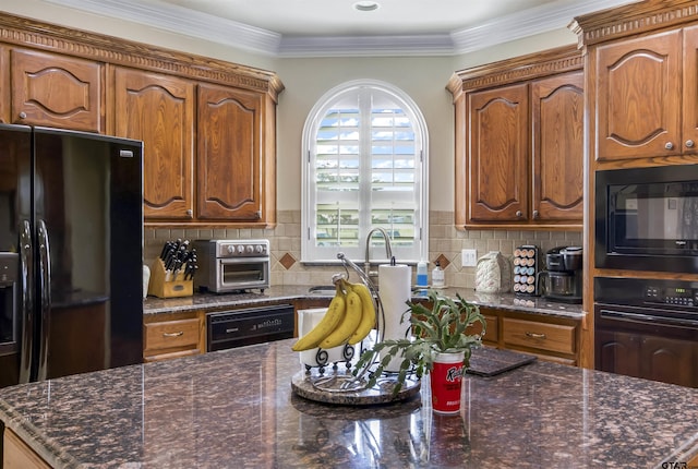 kitchen featuring crown molding, decorative backsplash, black appliances, and dark stone counters