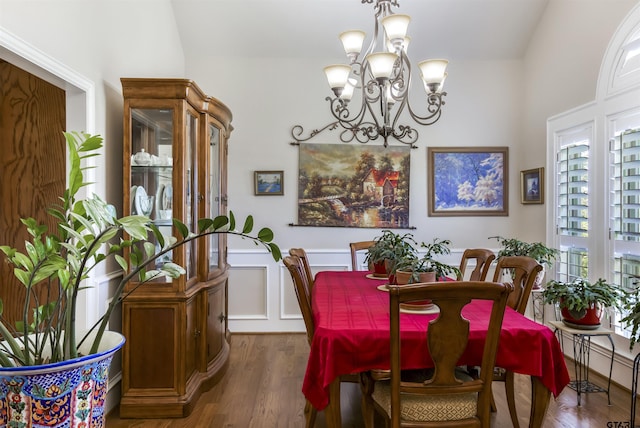 dining room featuring dark wood-type flooring, vaulted ceiling, and a notable chandelier