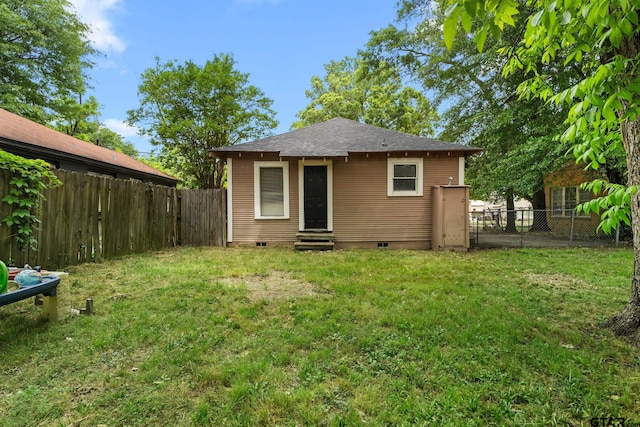 back of property with a lawn, crawl space, a fenced backyard, and entry steps