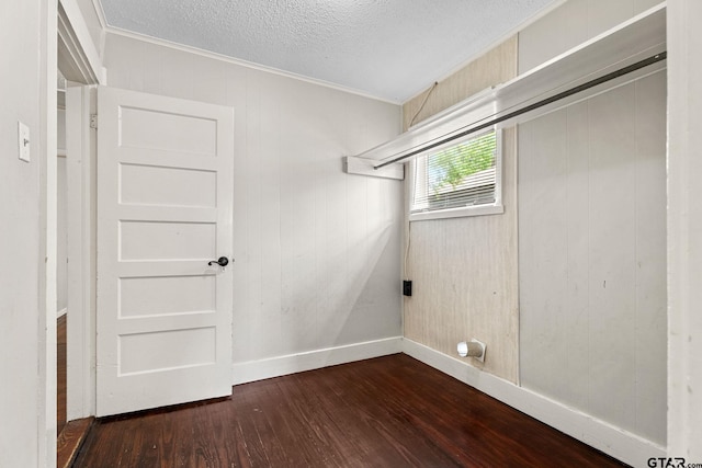 clothes washing area with crown molding, dark wood-style flooring, laundry area, a textured ceiling, and baseboards