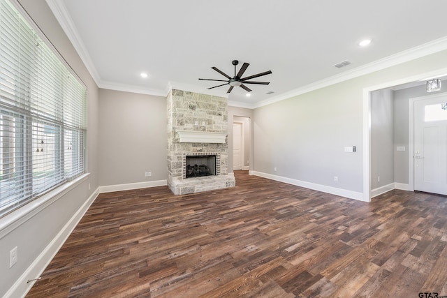 unfurnished living room with a stone fireplace, ceiling fan, dark hardwood / wood-style floors, and crown molding