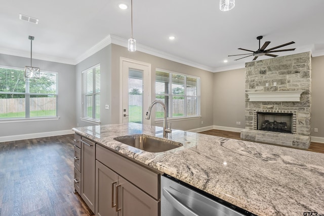 kitchen featuring a stone fireplace, dark hardwood / wood-style flooring, light stone countertops, hanging light fixtures, and sink