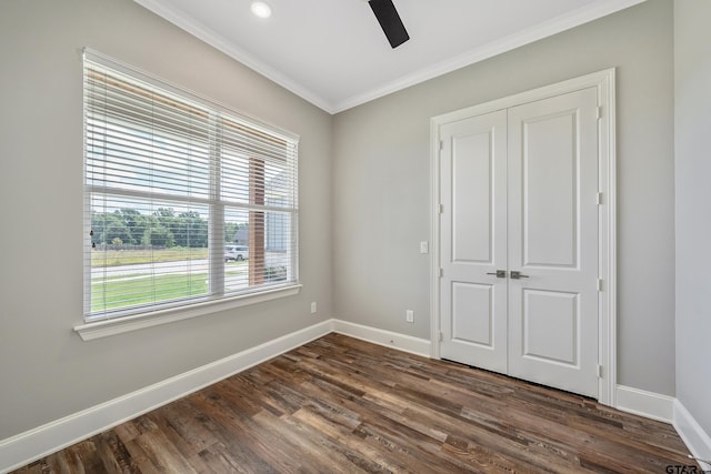 unfurnished bedroom featuring dark wood-type flooring, ceiling fan, a closet, and crown molding