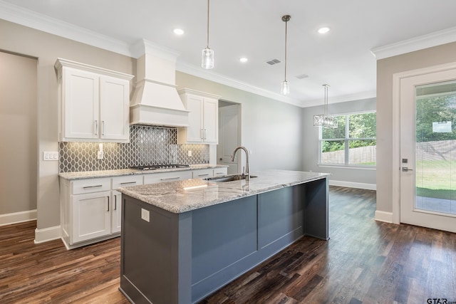 kitchen featuring white cabinets, hanging light fixtures, sink, a kitchen island with sink, and dark hardwood / wood-style floors