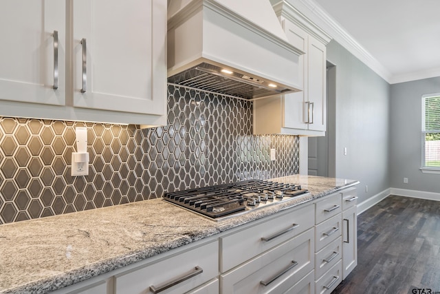 kitchen featuring stainless steel gas stovetop, white cabinets, custom exhaust hood, dark hardwood / wood-style floors, and crown molding