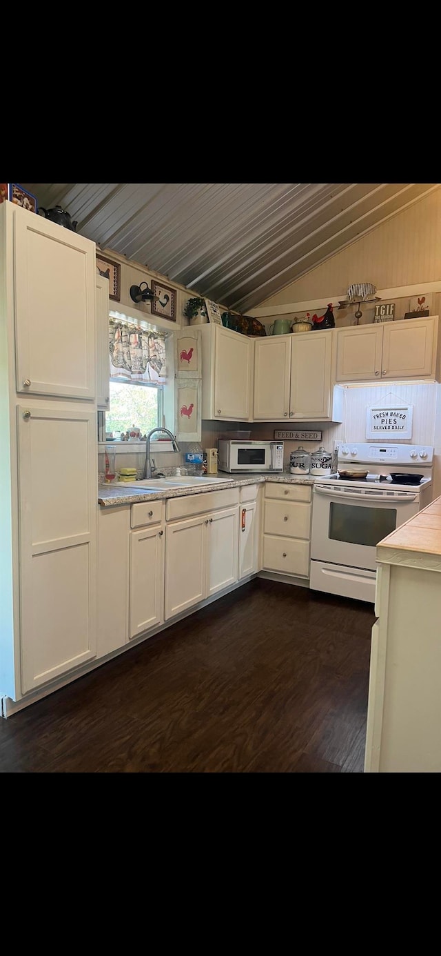 kitchen with sink, white appliances, white cabinets, dark wood-type flooring, and vaulted ceiling