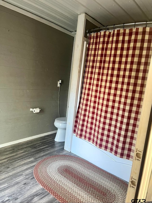 bathroom featuring shower / bath combo, wooden walls, hardwood / wood-style flooring, and toilet