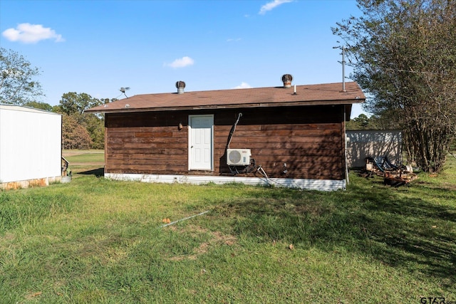 rear view of house featuring a wall mounted AC and a lawn