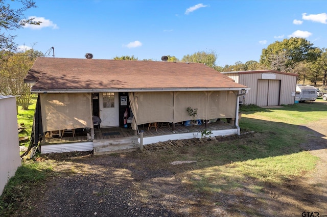 back of house featuring a lawn and an outbuilding