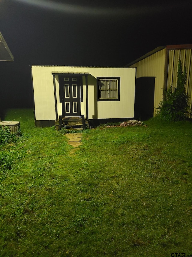 view of front of house with entry steps, a front lawn, and an outdoor structure