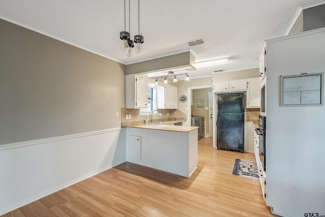 kitchen with white cabinetry, a textured ceiling, black refrigerator, sink, and light hardwood / wood-style flooring