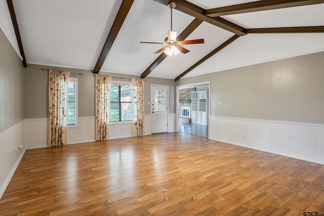 unfurnished living room featuring ceiling fan, light hardwood / wood-style flooring, and vaulted ceiling with beams