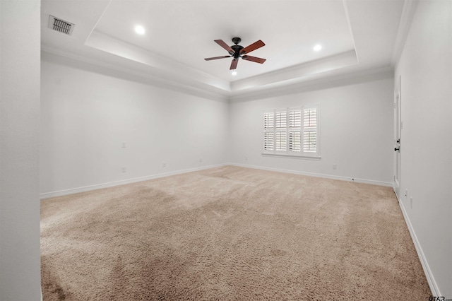 empty room featuring a tray ceiling, ceiling fan, carpet flooring, and ornamental molding