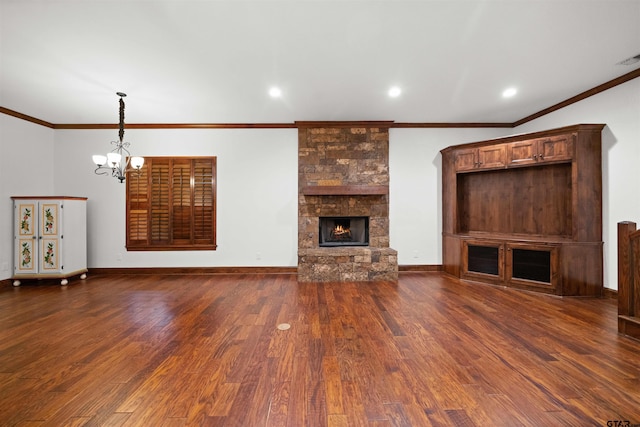 unfurnished living room featuring a fireplace, ornamental molding, dark wood-type flooring, and a notable chandelier