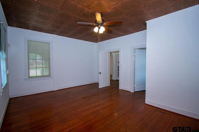 spare room with wood finished floors, baseboards, ceiling fan, and an ornate ceiling