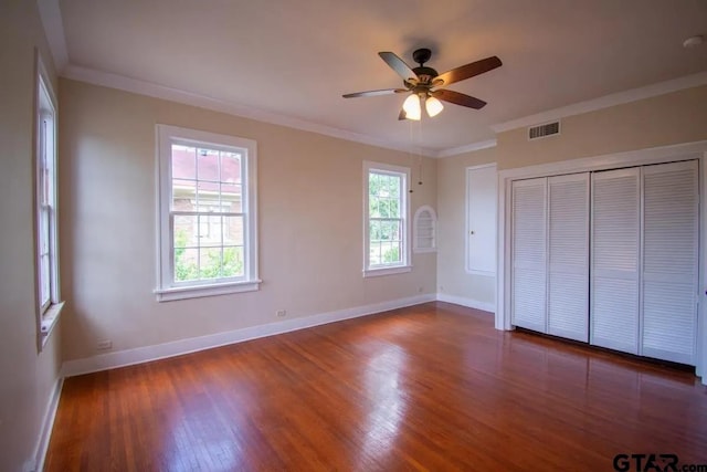 unfurnished bedroom with baseboards, visible vents, multiple windows, and wood finished floors