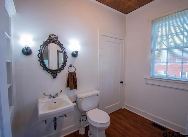 bathroom with visible vents, wood finished floors, toilet, baseboards, and a sink