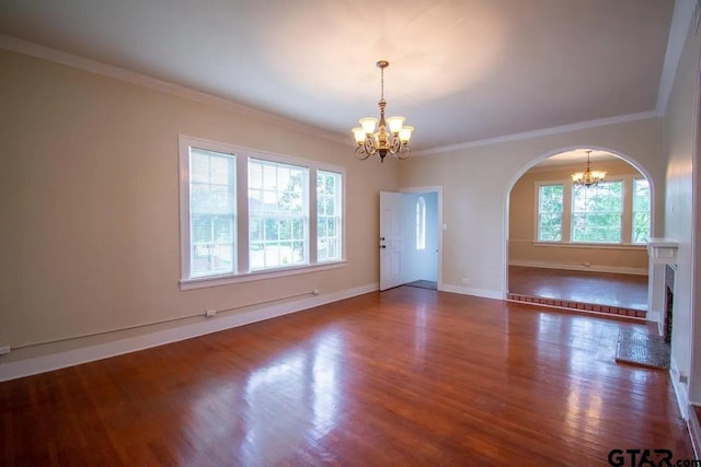 empty room with arched walkways, a chandelier, ornamental molding, and wood finished floors