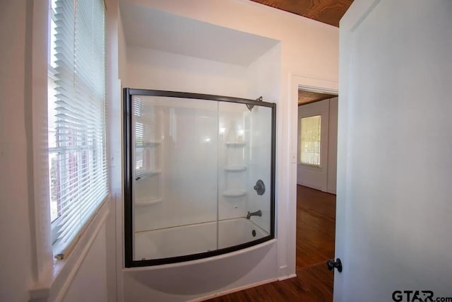 bathroom featuring wood finished floors and shower / bath combination with glass door