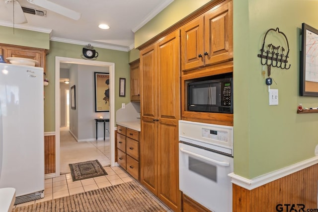 kitchen featuring white appliances, light tile patterned floors, and ornamental molding