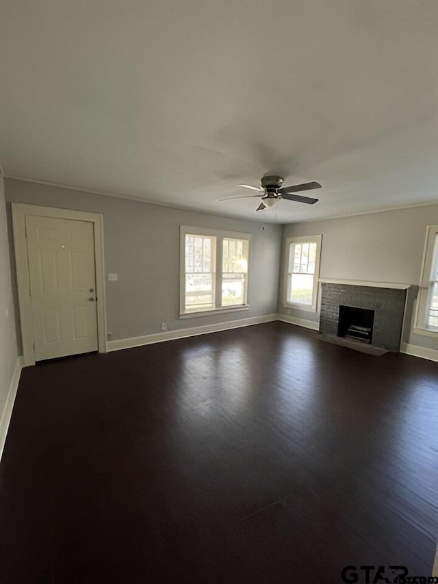 unfurnished living room with dark hardwood / wood-style flooring, a brick fireplace, and ceiling fan