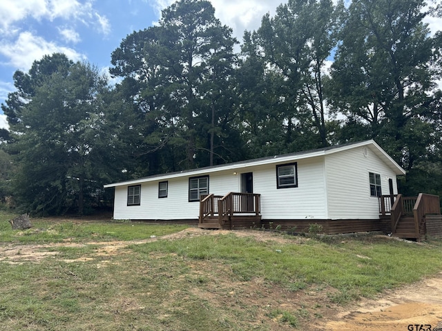 view of front facade featuring a front yard and a wooden deck